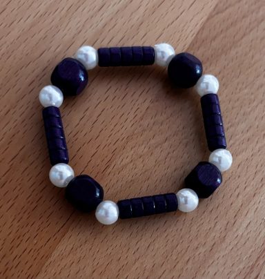 Armbänder aus lila und weißen Perlen in runder Form.