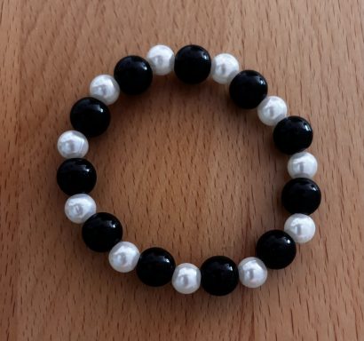 Schmuckarmband aus schwarzen und weißen Perlen, abwechselnd angeordnet.